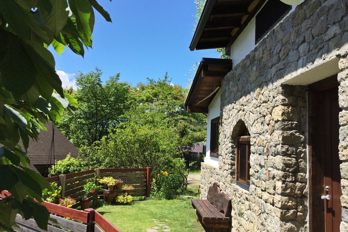 石头砌体房屋，一个草屋顶和石头小屋，周围环绕着一个花园，四季色彩缤纷。