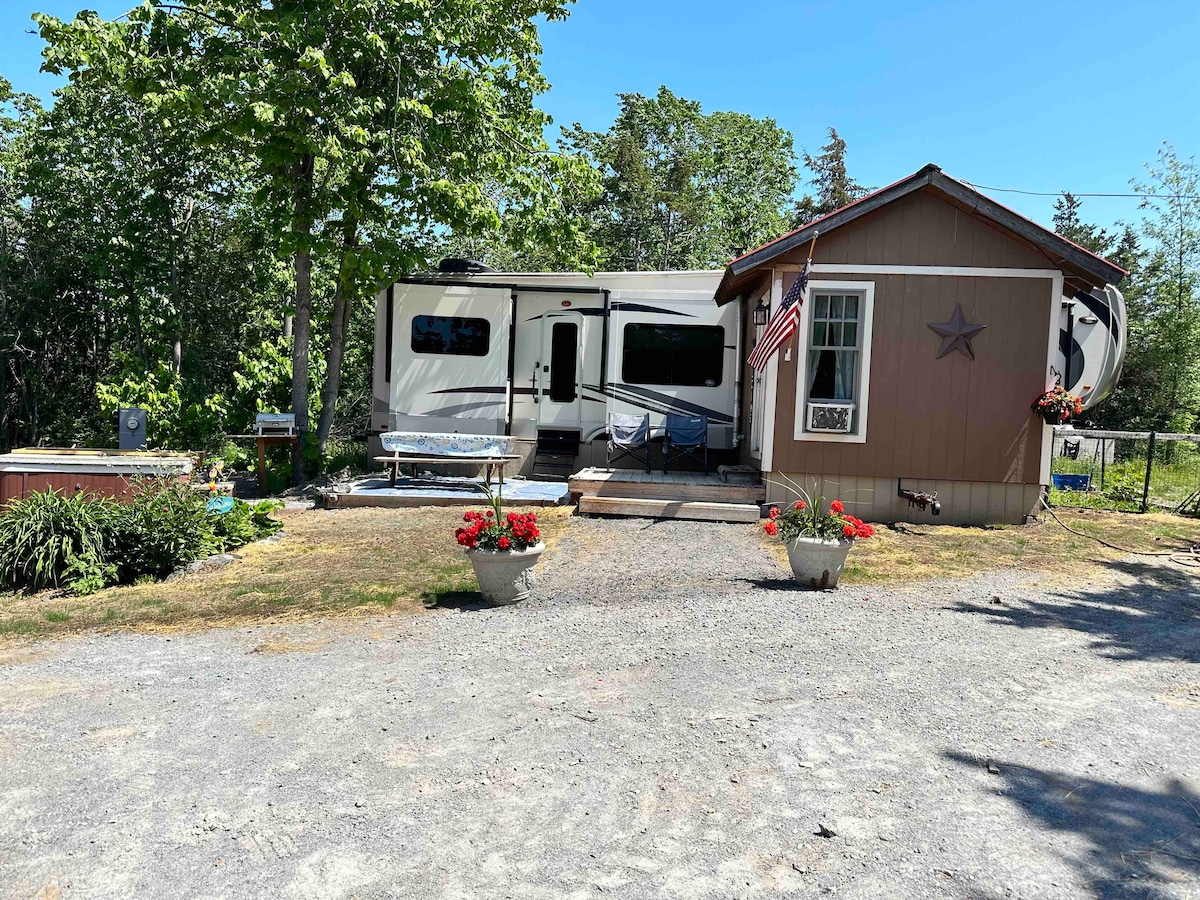 Rustic 5th wheel camper close to lake.