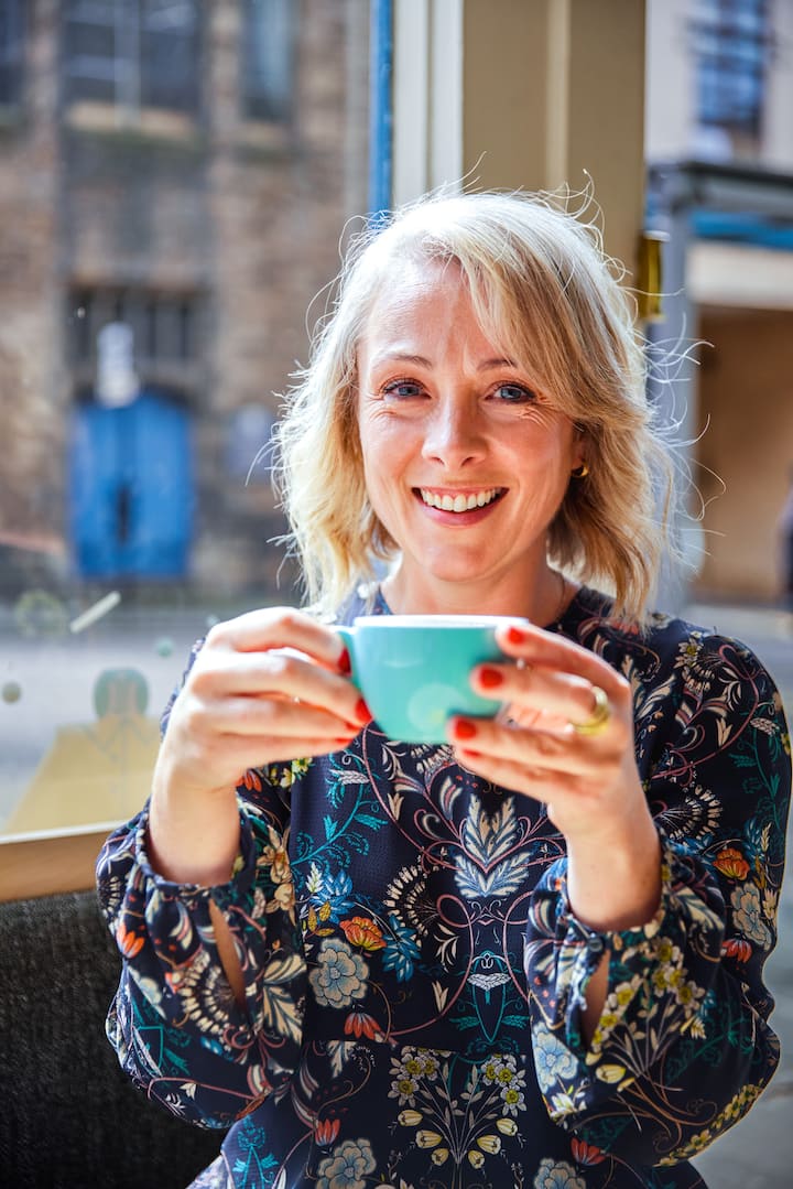 Image of Catherine smiling with a cup of coffee