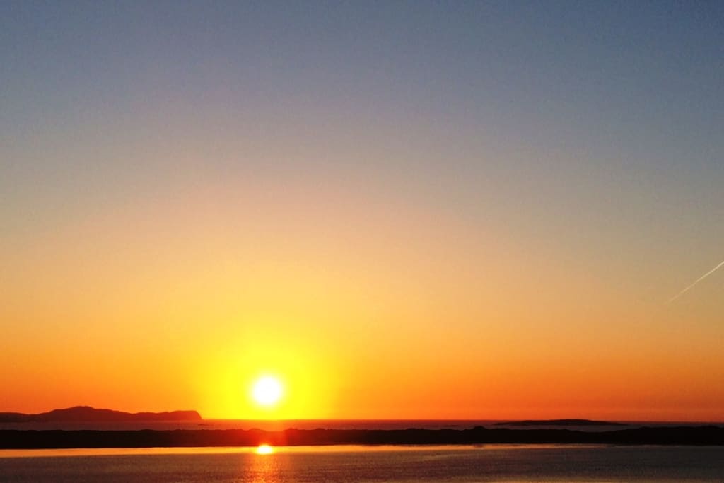 the sun setting over owey island from behind my house