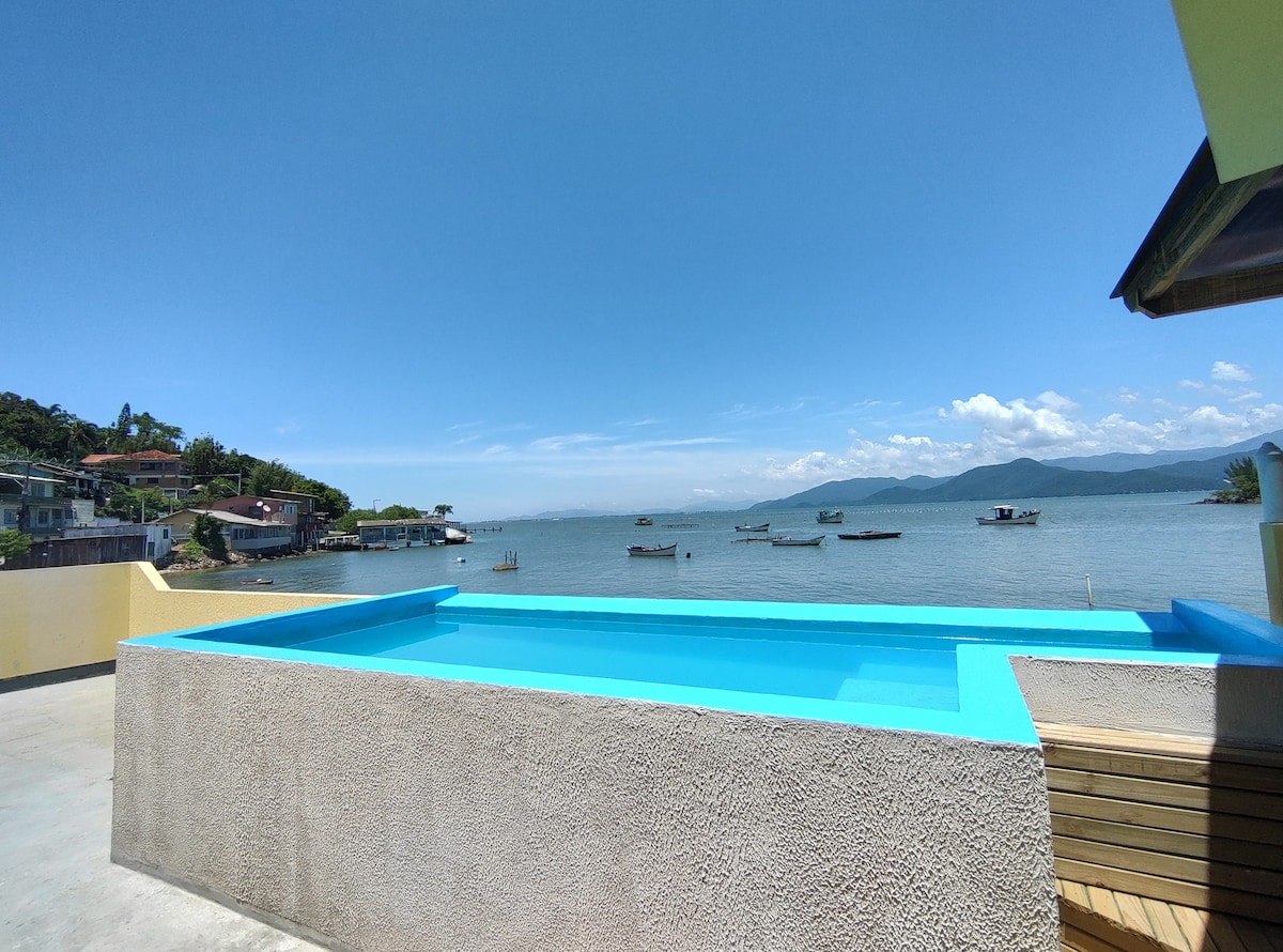 Beira-mar, piscina e vista montanha com pôr do sol