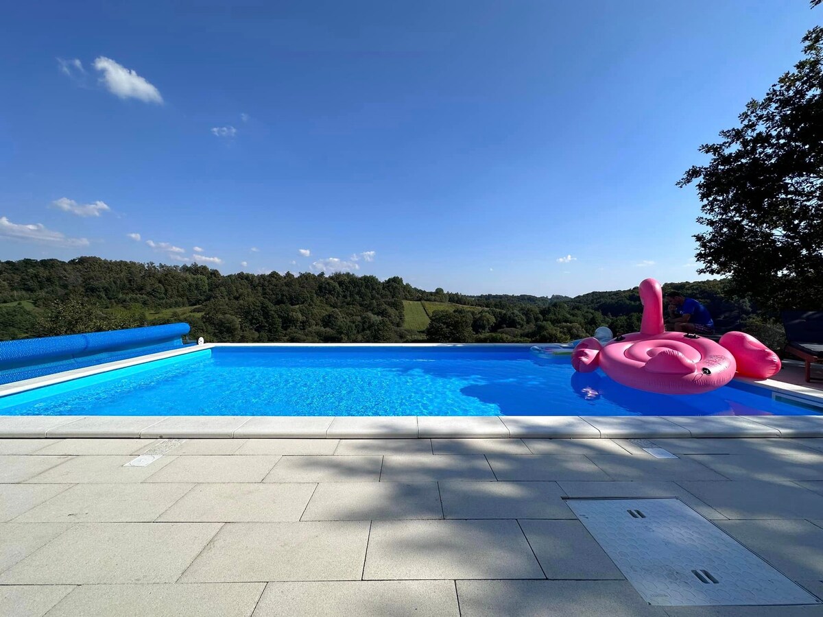 A villa with a pool and hot tub in nature.