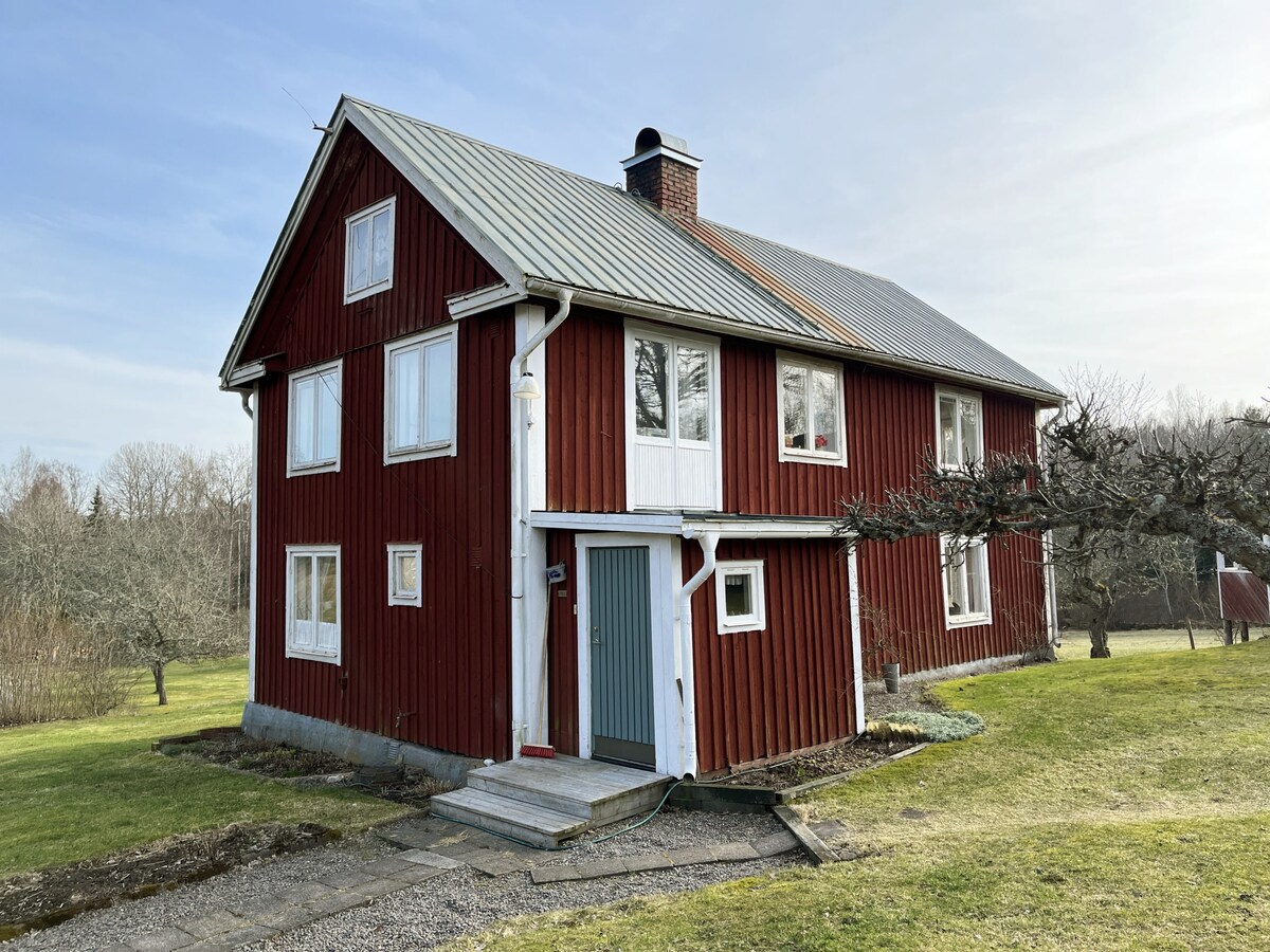 Red cottage located close to forest and land outsi